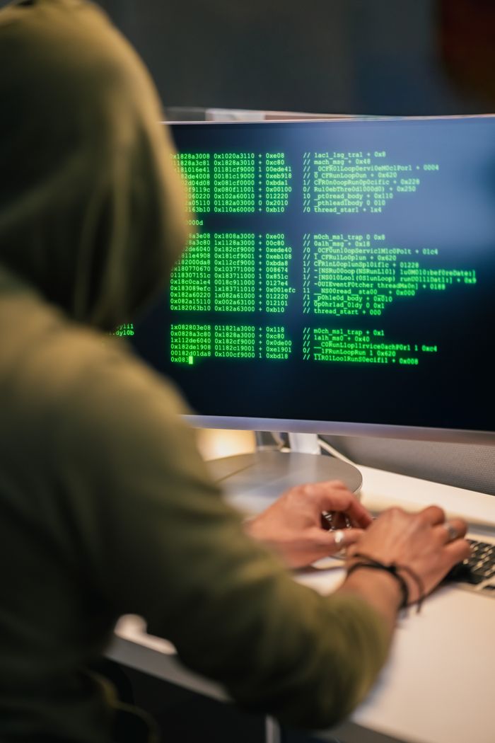 Crafting Captivating Headlines: Your awesome post title goes here Person wearing a hoodie typing code on a computer screen with green text, depicting hacking scene.