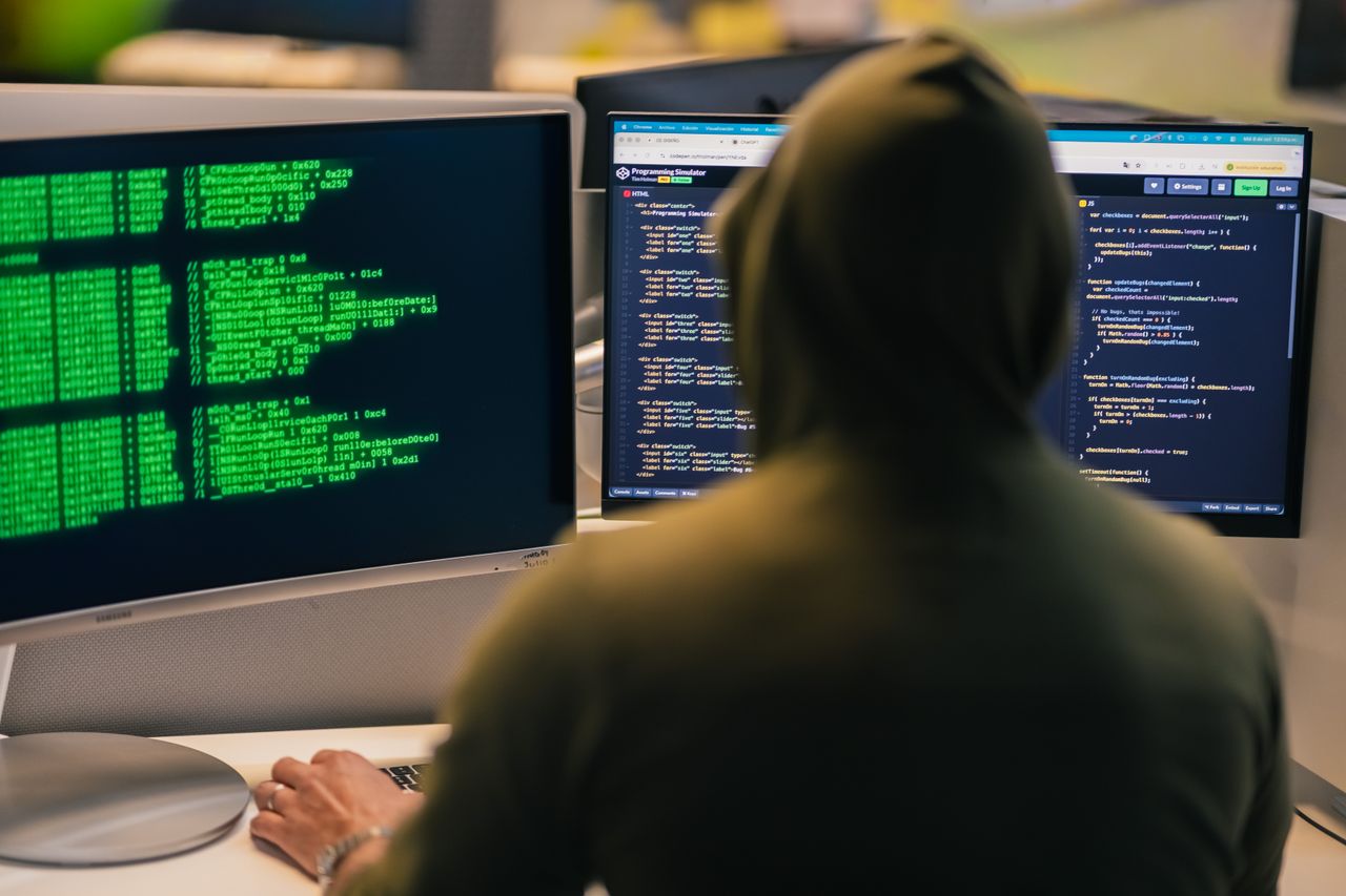 Mastering the First Impression: Your intriguing post title goes here A person in a hoodie coding on dual monitors, depicting cybersecurity and hacking themes.